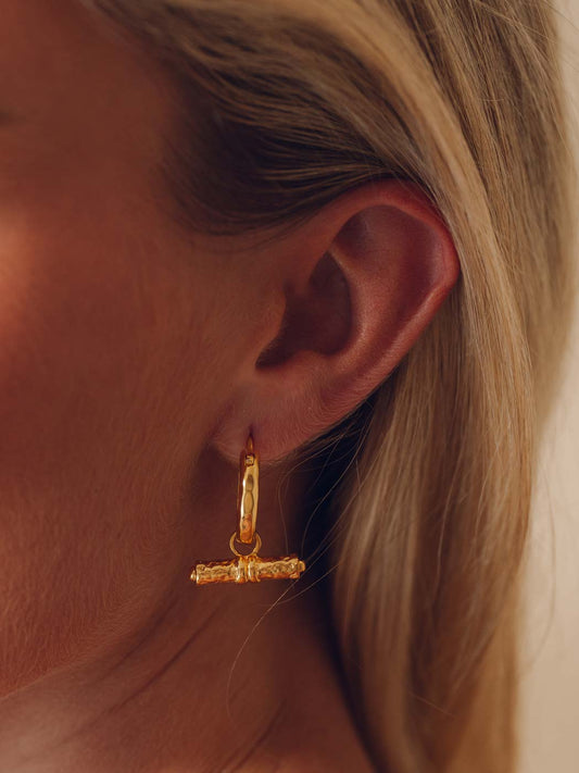 Gold hoop earring worn by a person with blonde hair.