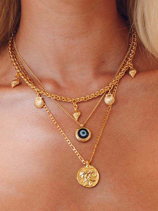 Gold necklaces with various pendants on a person's neck