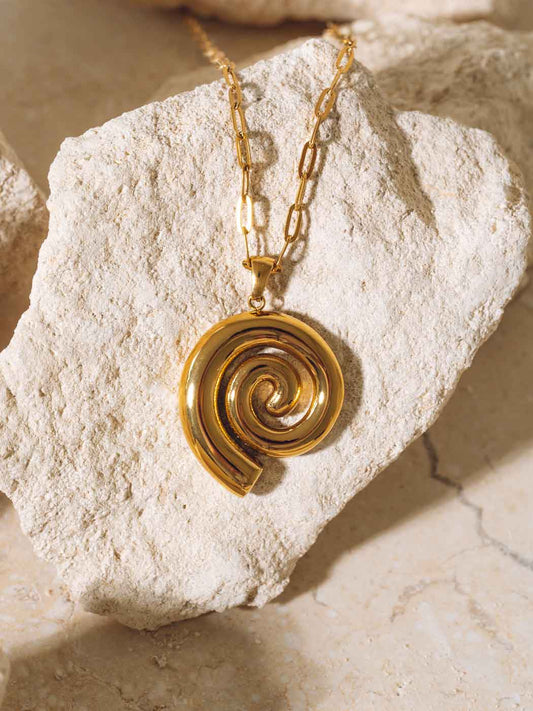 Gold spiral pendant necklace on a textured stone surface