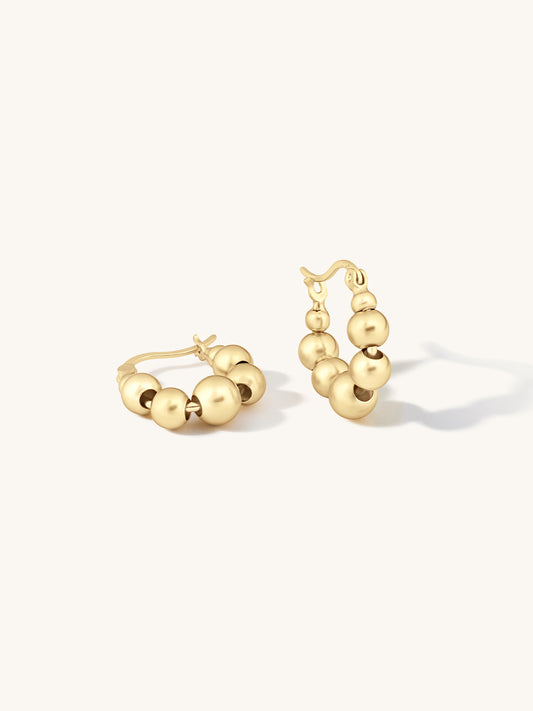 gold uniquely shaped hoop with small bubble shapes circling the hoop