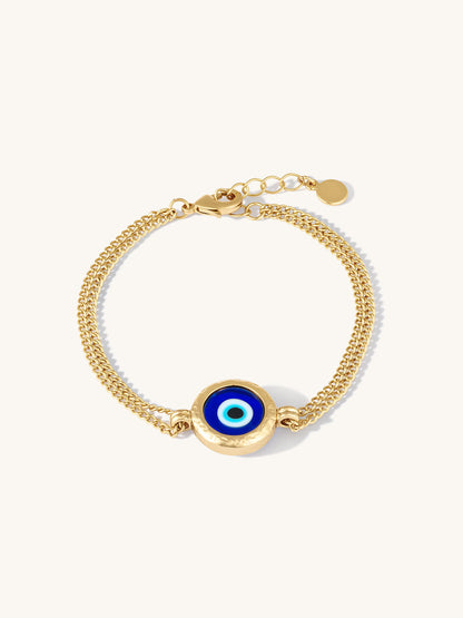 Gold bracelet with a blue evil eye charm on a white background