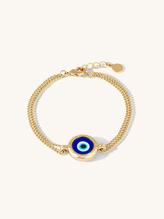 Gold bracelet with a blue evil eye charm on a white background