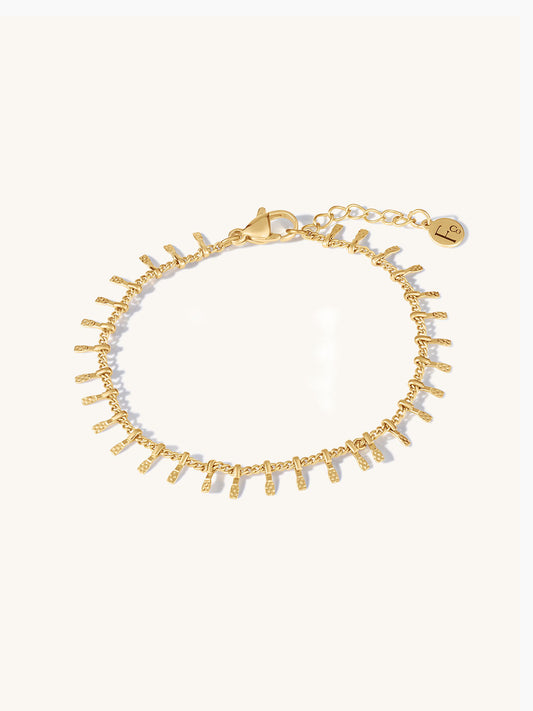 Gold bracelet with textural bars on a white background