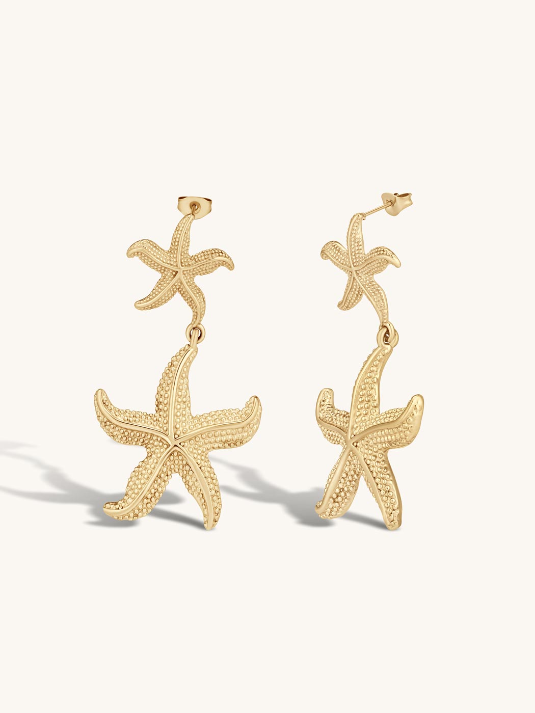 Gold statement starfish earrings on a white background