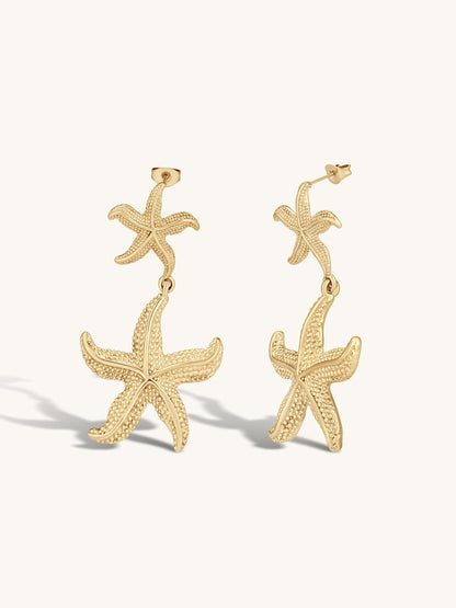 Gold statement starfish earrings on a white background