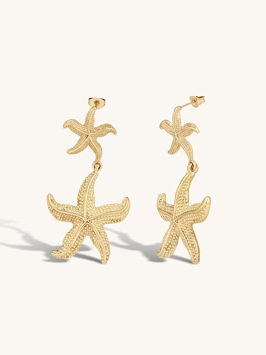 Gold statement starfish earrings on a white background