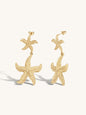 Gold statement starfish earrings on a white background