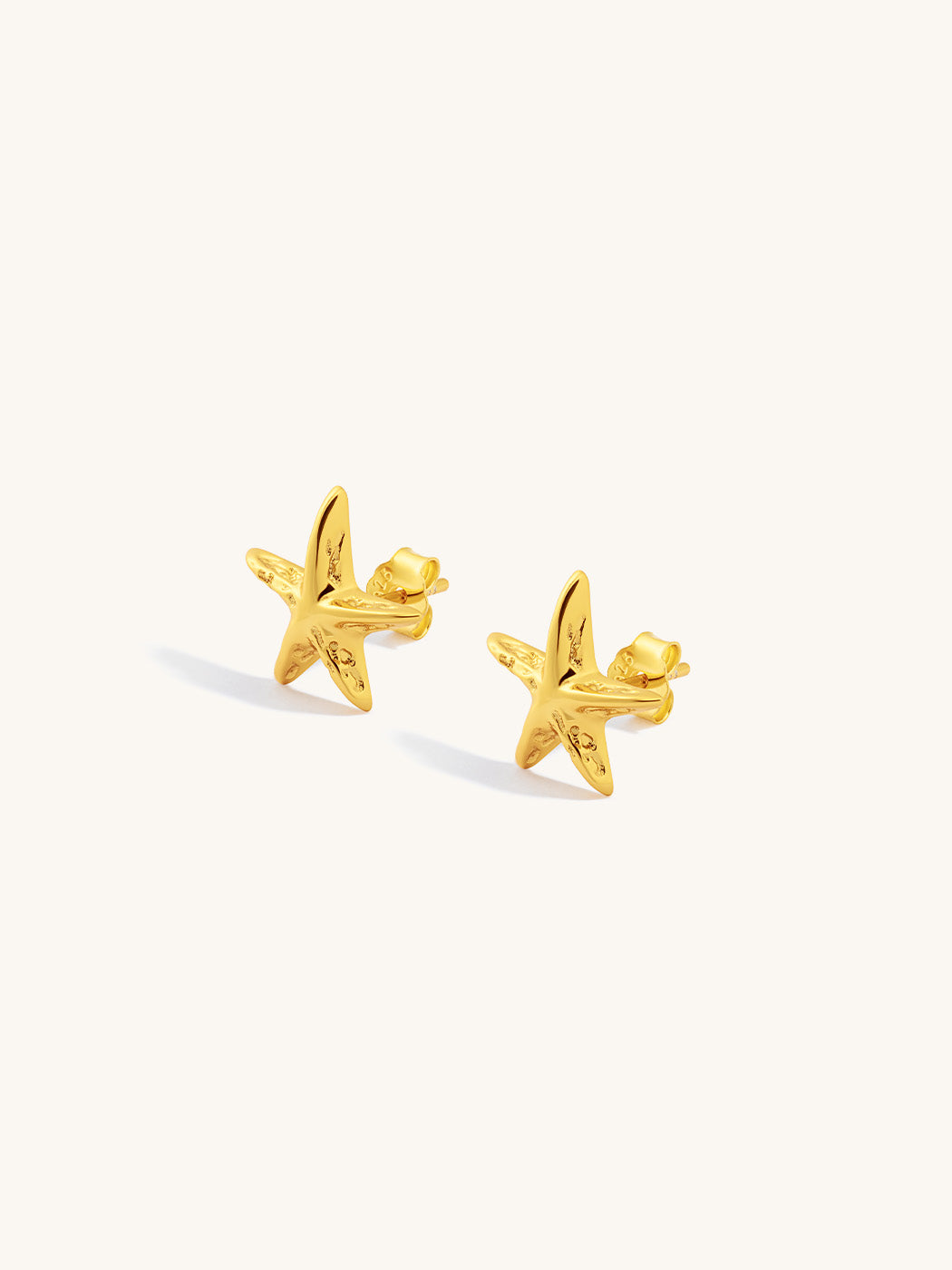 Gold starfish earrings on a white background