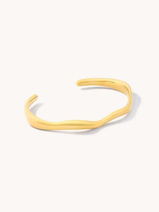 Gold irregular shaped bangle on a white background