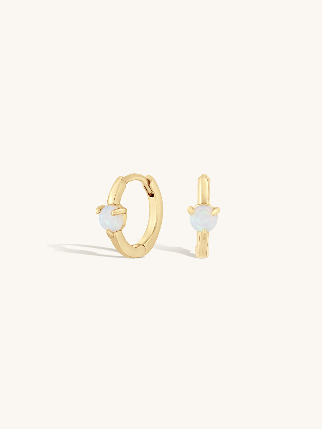 gold huggies with round opal gemstone in center on white background