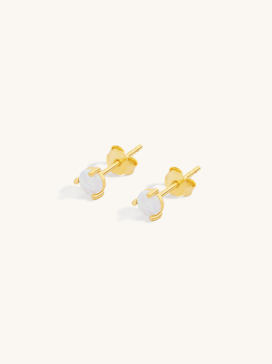 Gold stud earrings with white opal round stones on a white background