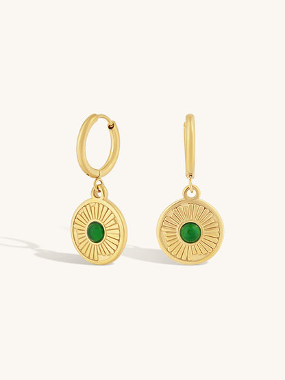 round simple gold hoop with larger textured gold pendant and small round emerald gemstone in the center