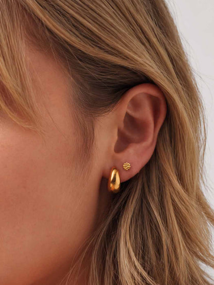 Gold beaded stud worn by a person with blonde hair on a neutral background