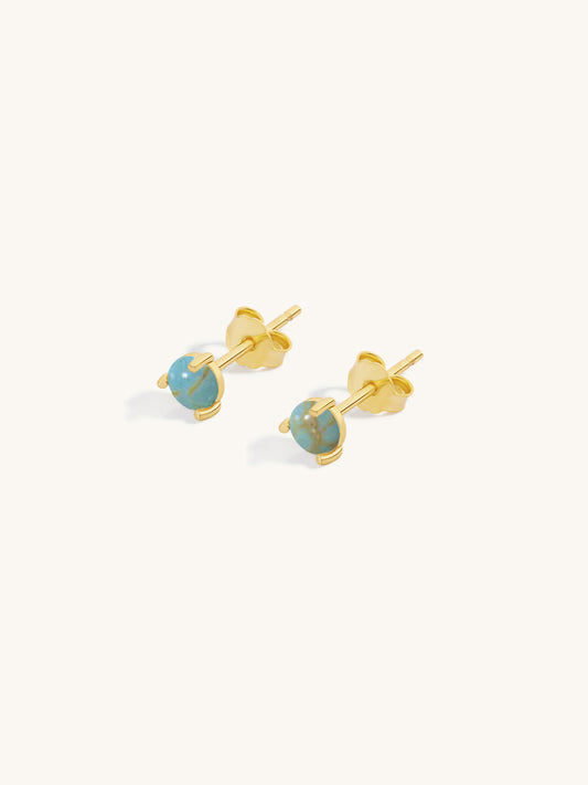 Gold earrings with turquoise stones on a white background