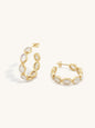 A pair of gold hoop earrings with oval milky white raw cut moonstone inlays, displayed on a clean off-white background.