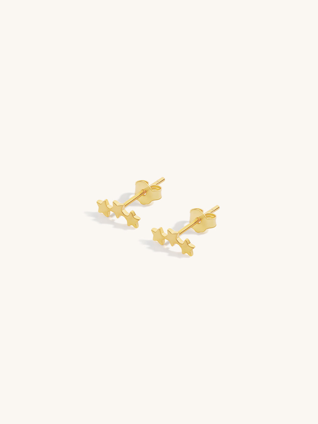 Pair of gold triple star crawler stud earrings on a white background