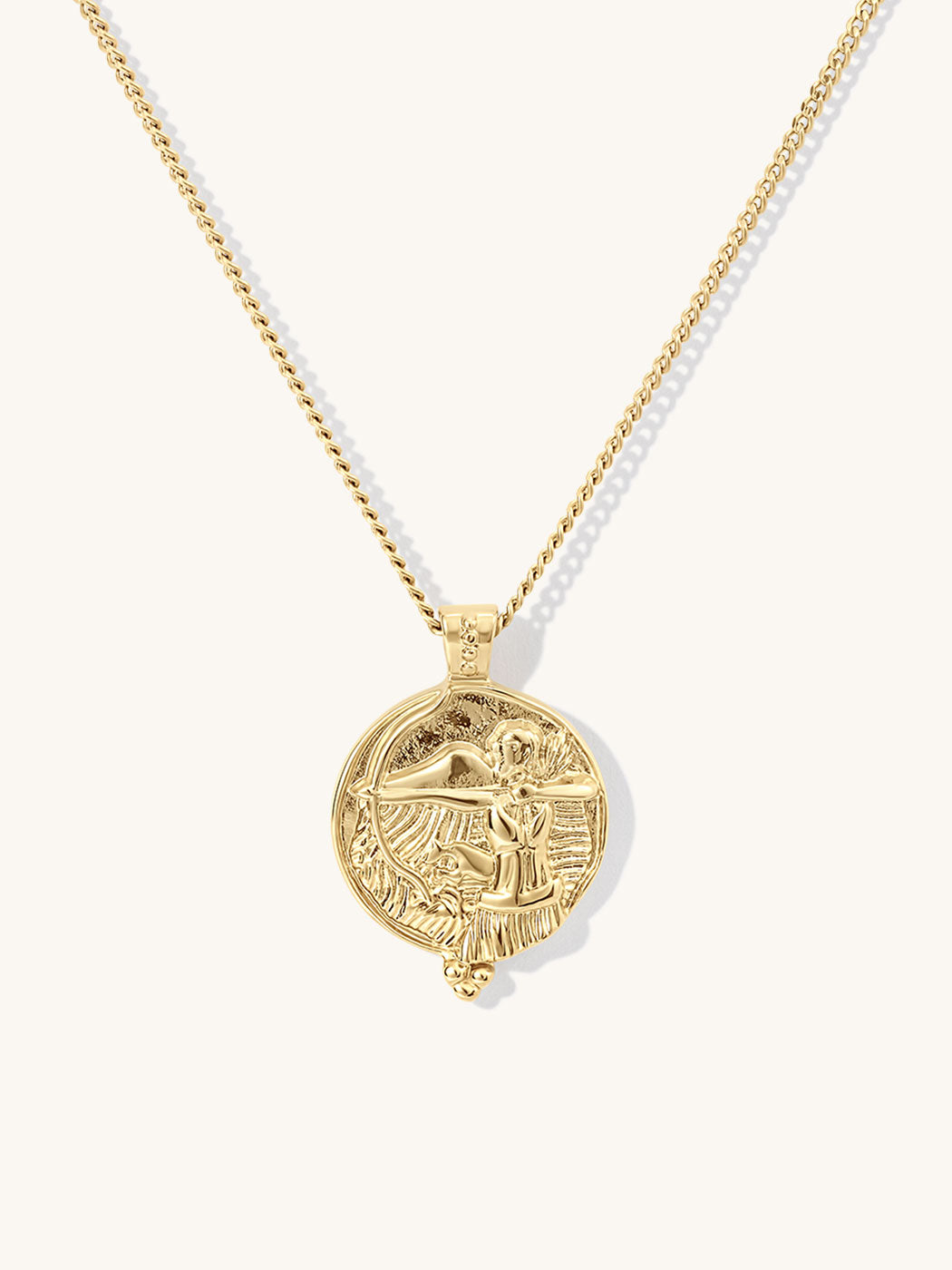 A gold chain necklace featuring a circular pendant with agoddess artemis figure, displayed against a clean off-white background.