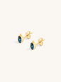 Gold bohemmian style earrings with blue gemstones on a white background