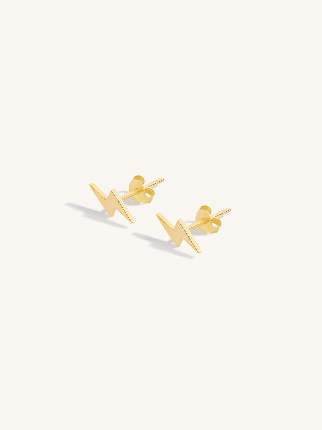 Gold lightning stud earrings on a white background