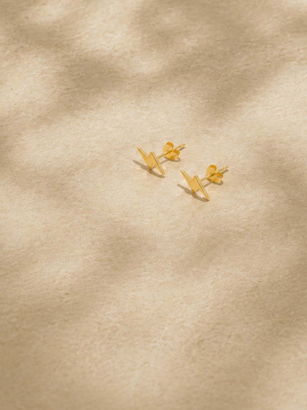 Gold lightning studs on a beige fabric background