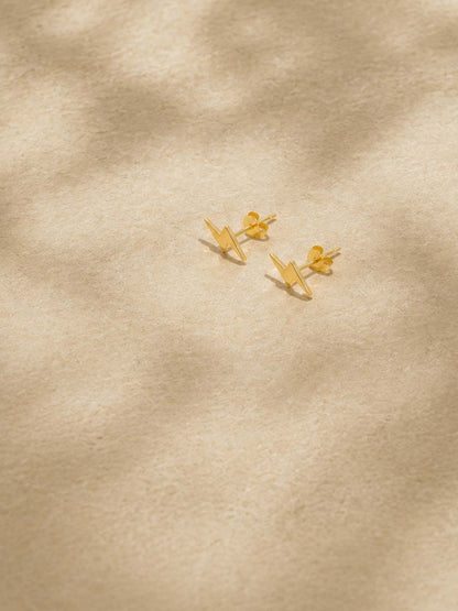 Gold lightning studs on a beige fabric background