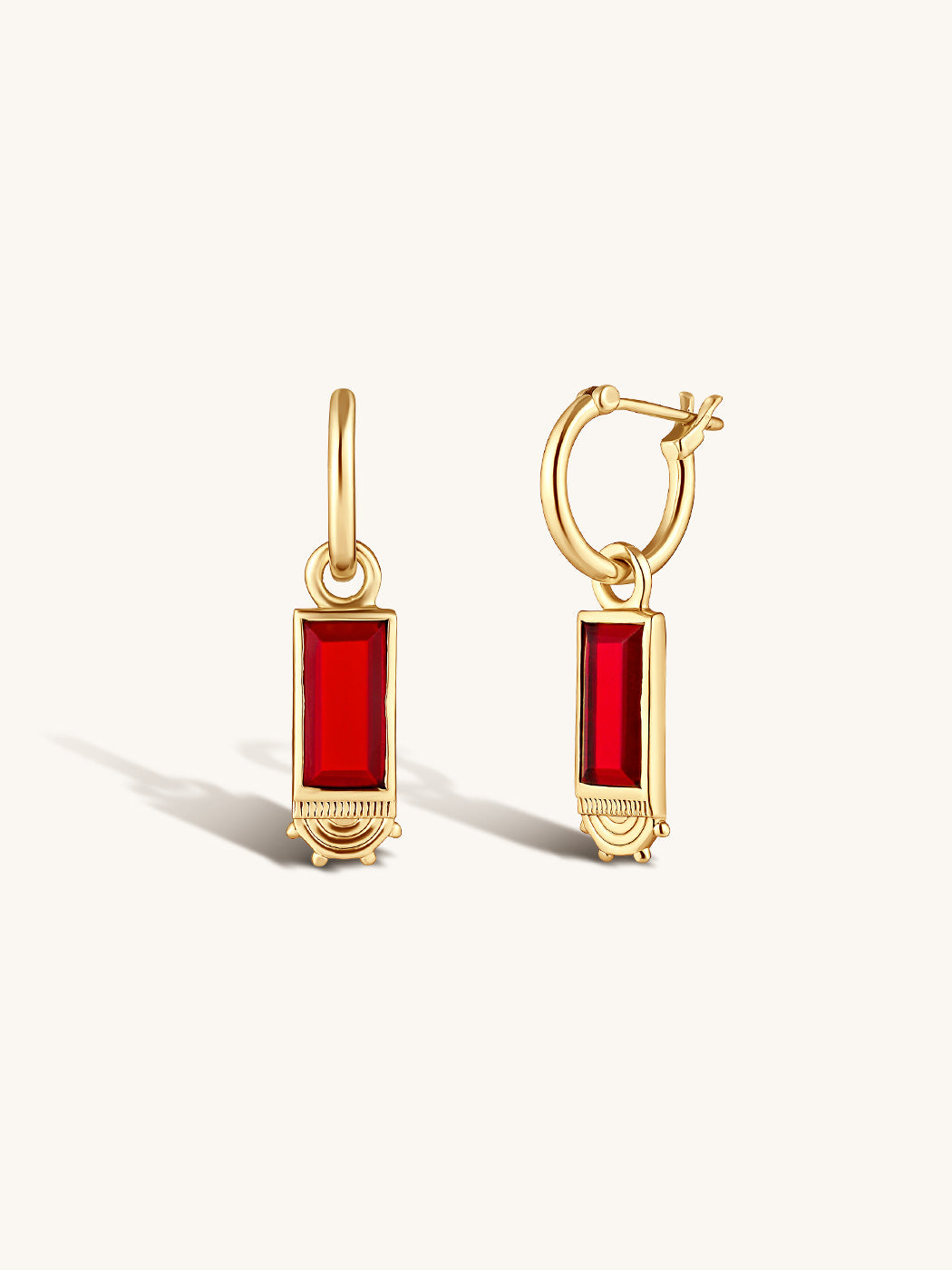 rectangular ruby gemstones set in gold framing with intricate detailing on rounded smooth gold hoops