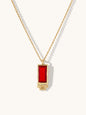 A gold chain necklace with a rectangular ruby gemstone pendant, displayed on a clean off-white background with soft shadows.